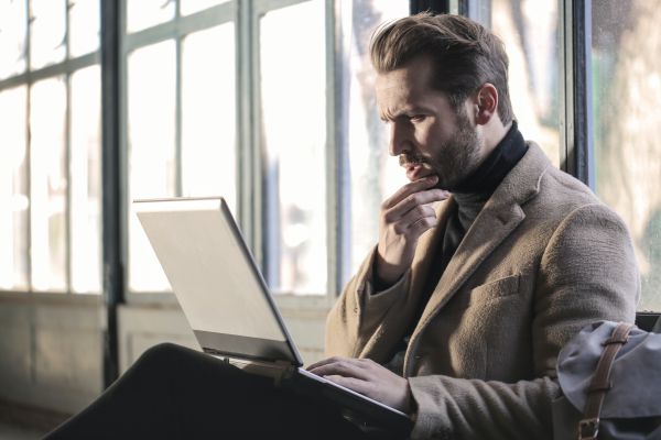 man thinking at a laptop